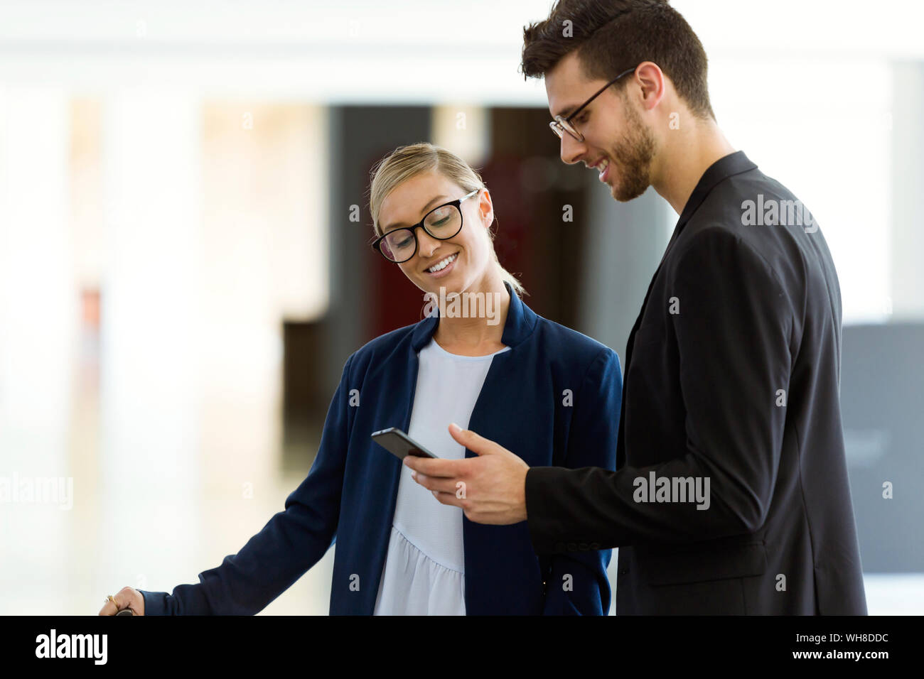 Zwei lächelnde junge Geschäftspartner mit einem Smartphone Stockfoto