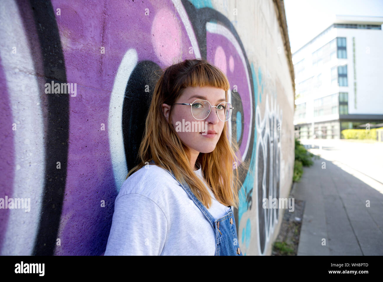 Junge Frau vor lila Graffiti Stockfoto