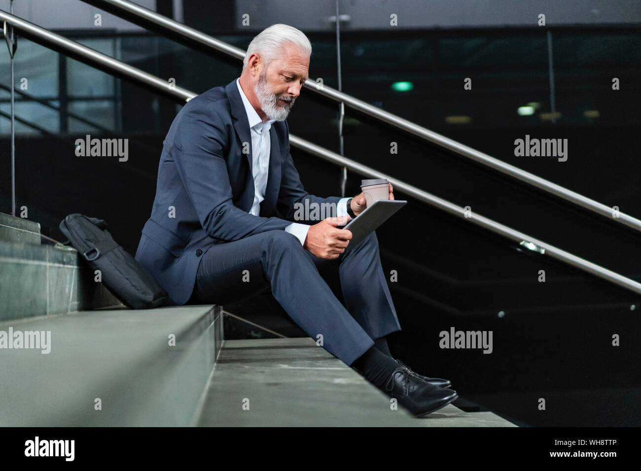 Reifen Geschäftsmann sitzt auf der Treppe mit Tablet Stockfoto