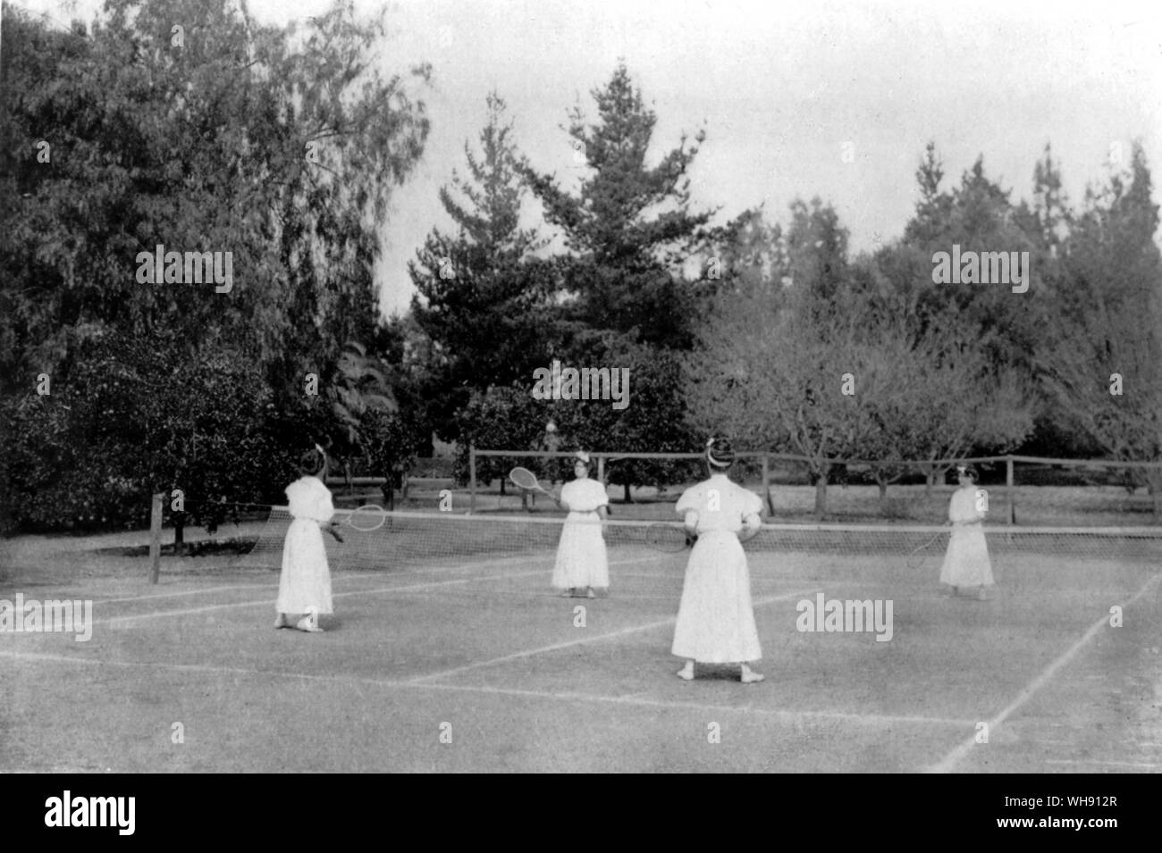 Mai Sutton (hinter dem Netz auf der linken Seite) und ihre Schwestern zu Hause Tennisplatz in Pasadena, Kalifornien, USA. Stockfoto