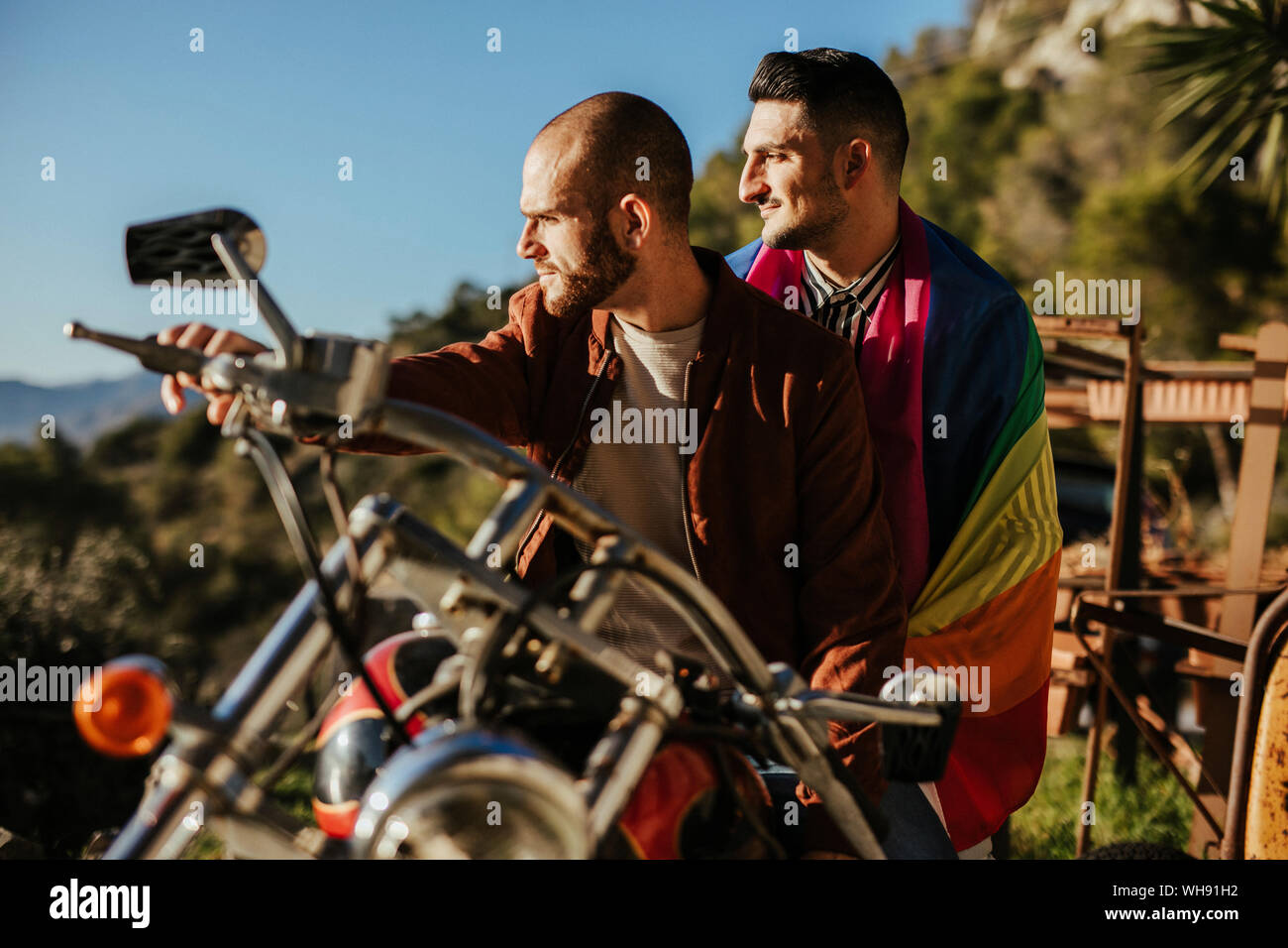 Ein schwules Paar mit Gay Pride Flagge auf einem Motorrad Stockfoto
