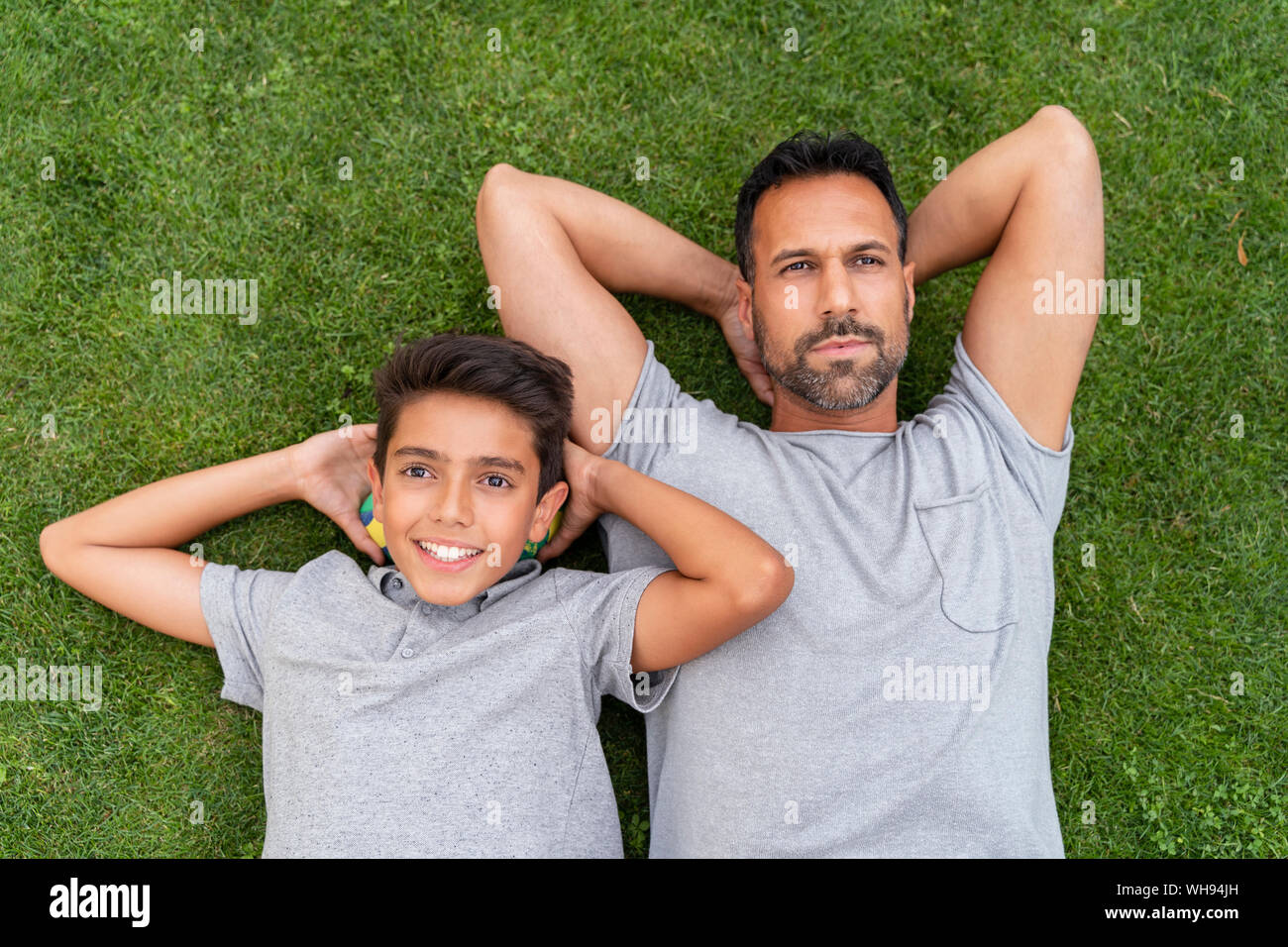 Vater und Sohn zusammen im Gras liegend Stockfoto