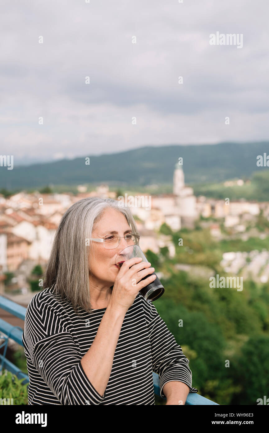 Portrait der älteren Frau trinkt Kaffee auf ihrer Dachterrasse, Belluno, Italien Stockfoto