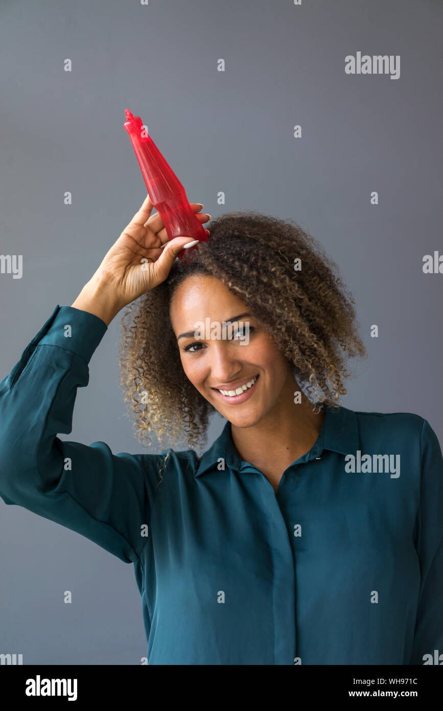 Portrait von lächelnden jungen Frau mit rotem Kunststoff Flasche auf dem Kopf Stockfoto