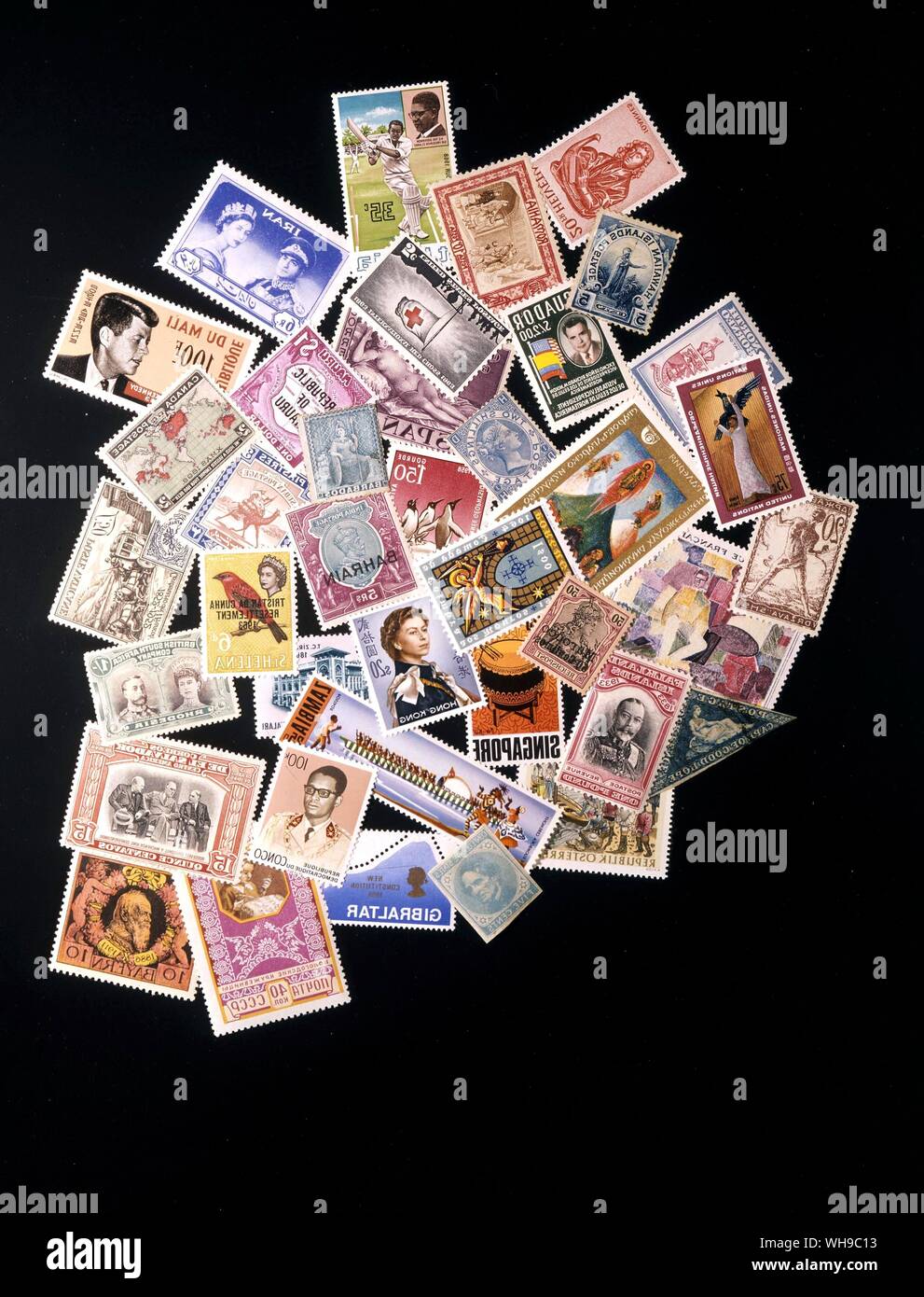 Eine Reihe von Briefmarken aus der ganzen Welt zufällig in einem Haufen gestapelt auf einem schwarzen Hintergrund. Stockfoto