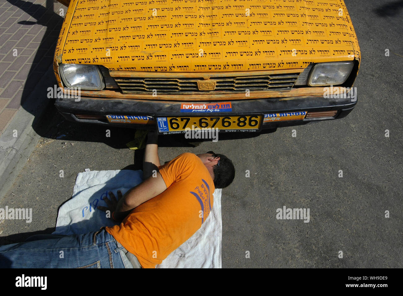 Eine jüdische Siedler Instandsetzung ein Auto mit einem Slogan lautet "ein Jude nicht ein Jude" in Neve Dekalim jüdische Siedlung wenige Tage vor der Evakuierung der jüdischen Siedlungen im Gazastreifen vertreiben eingerichtet Stockfoto