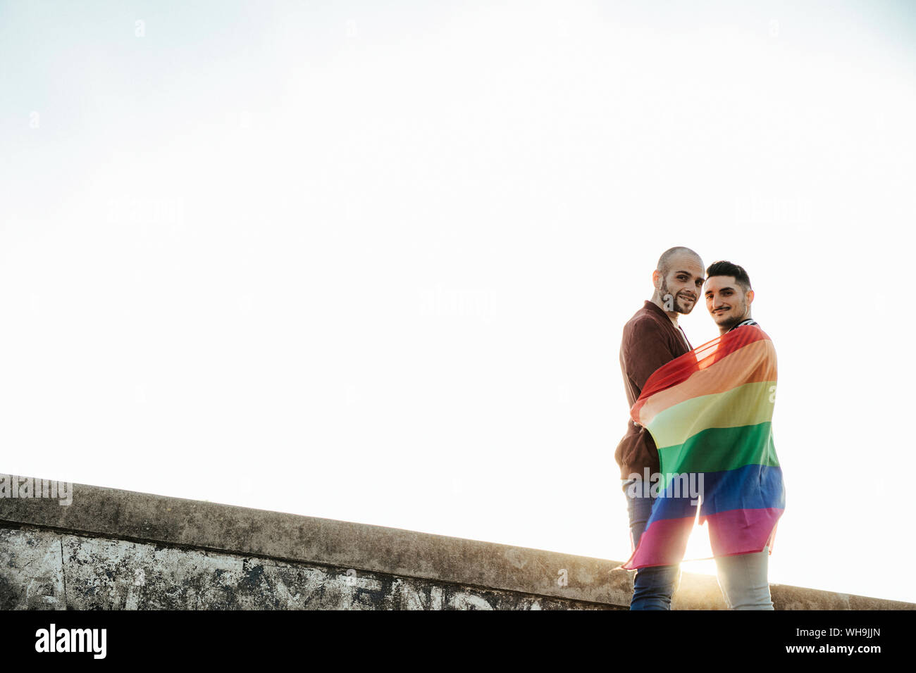 Portrait von lächelnden homosexuelles Paar mit Gay Pride flag Stockfoto