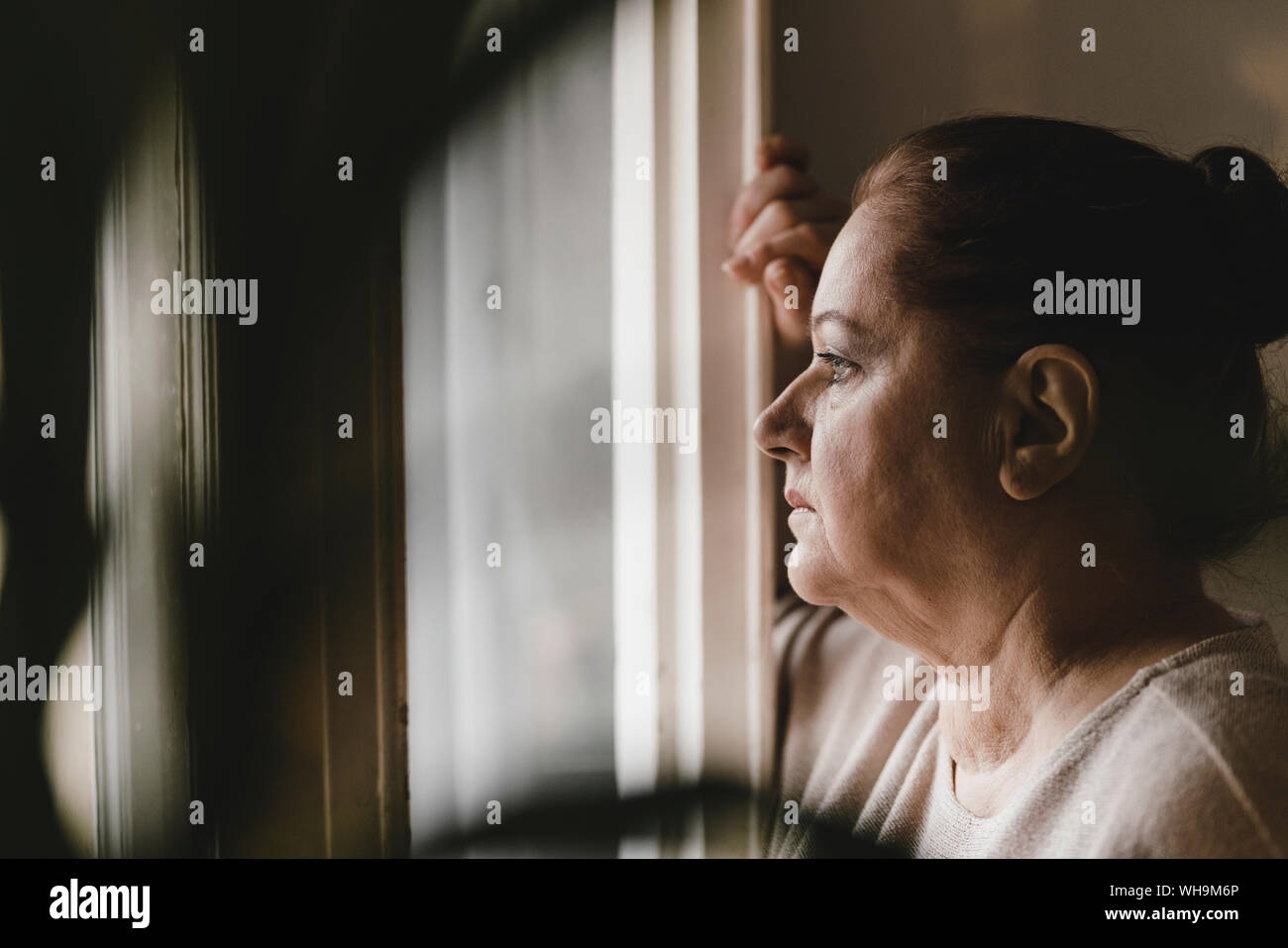 Ernst senior Frau Blick aus Fenster zu Hause Stockfoto
