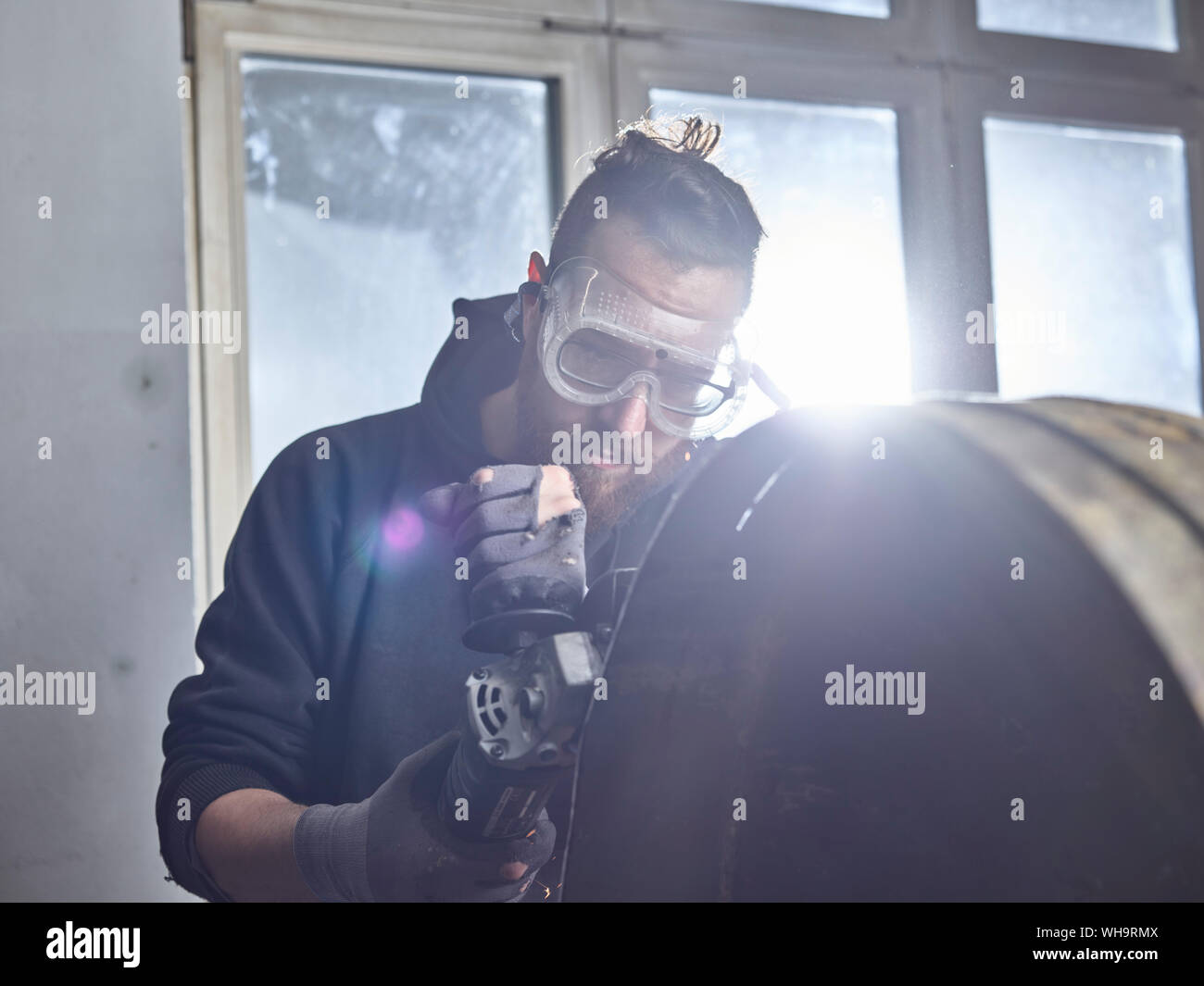 Mann bei der Arbeit auf Metall Container mit einem Schleifer Stockfoto