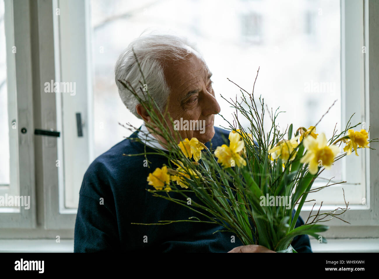 Älterer Mann mit Blumen zu Hause Stockfoto
