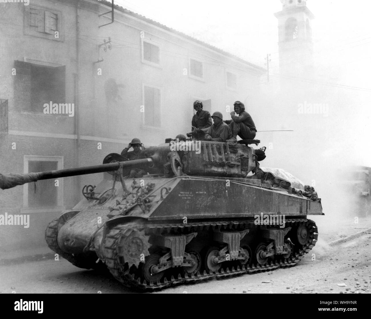 WW2: Ein Panzer und Fahrzeuge der US-fünfte Armee bewegen sich durch eine Stadt im Fluss Po, Italien, auf dem Weg nach vorne. 26. April 1945. Stockfoto