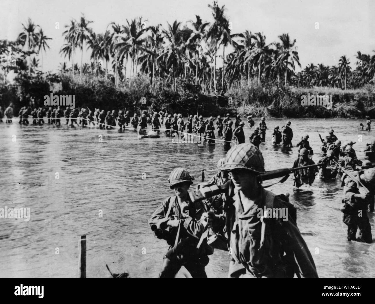 US-Truppen auf Leyte Island. Mit einem Seil als Führer von Ufer zu Ufer, Soldaten der US 7th Division Datei über das seichte Wasser des Flusses Marahang, Leyte Island, als sie auf dem Weg zu japanischen Positionen in den Hügeln in der Nähe von Santa Ana voraus. Trotz verräterische Flüsse, die Amerikanische und die phillipino Kräfte waren die langsame, aber stetige Fortschritte gegen die verstärkte feindliche Einheiten in der Gegend. Stockfoto