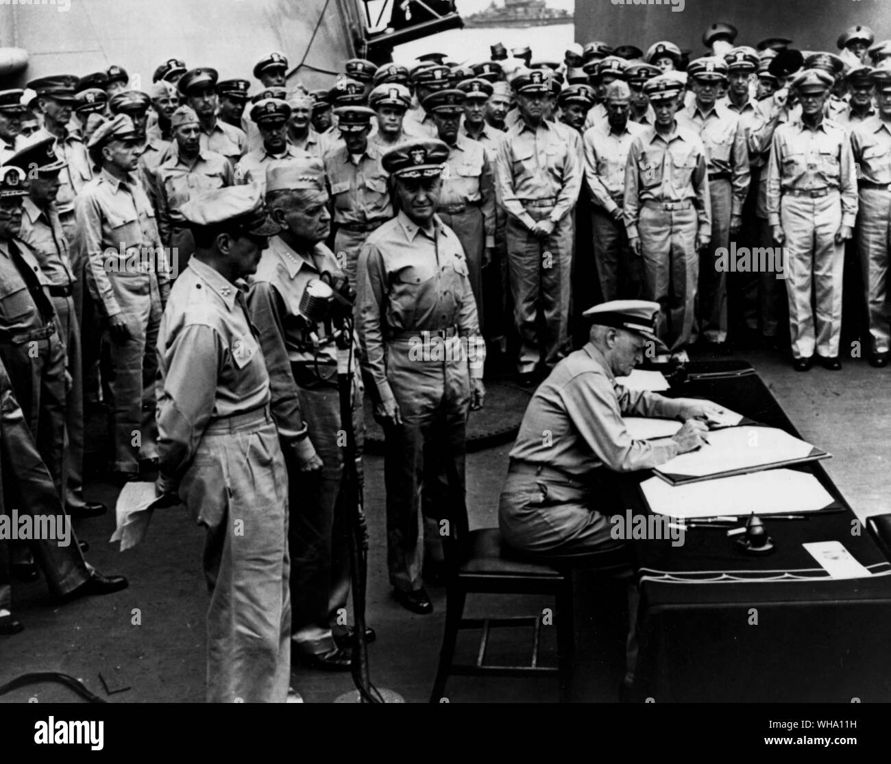 WW2: Bucht von Tokio, Japan. Fleet Admiral Chester Nimitz W Zeichen der japanischen Kapitulation Dokument an Bord der Flugzeugträger, die USS Missouri (BB-63). Auf der Suche auf der linken Seite sind: General Douglas MacArthur, Admiral William F Halsey und hinteren Admiral Forrest P Sherman. Stockfoto