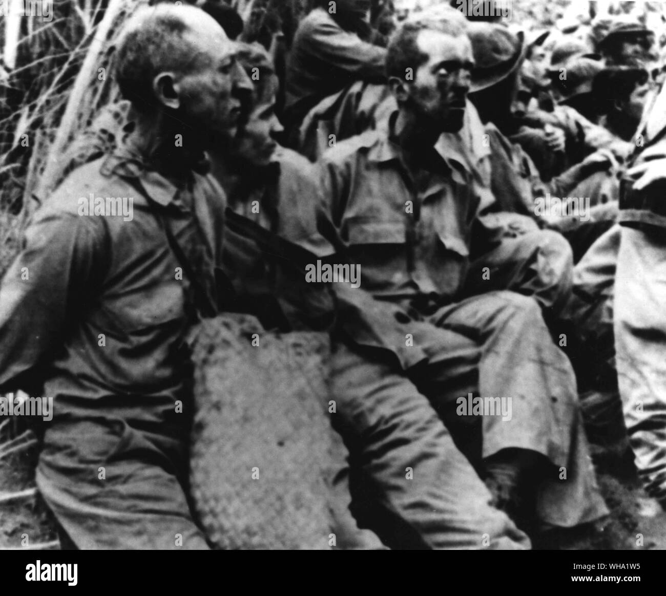 WW2: Republik der Philippinen. Ein Blick auf Samuel Stenzler, Frank Speer und James MCO. Gallagher, die Gefangenen mit ihren Händen hinter dem Rücken sitzend mit den amerikanischen und philippinischen Gefangenen der Japanischen gebunden. Diese Männer sind auf der 'March Of Death" von Bataan in Cabanatuan Gefangenenlager. Stockfoto