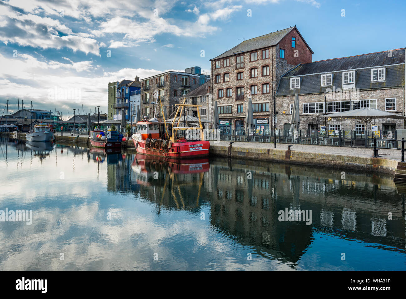 Fischerboote vertäut am Sutton Harbour, mit Geschäften und Cafés am Kai, die Barbican, Plymouth, Devon, England, Vereinigtes Königreich, Europa Stockfoto