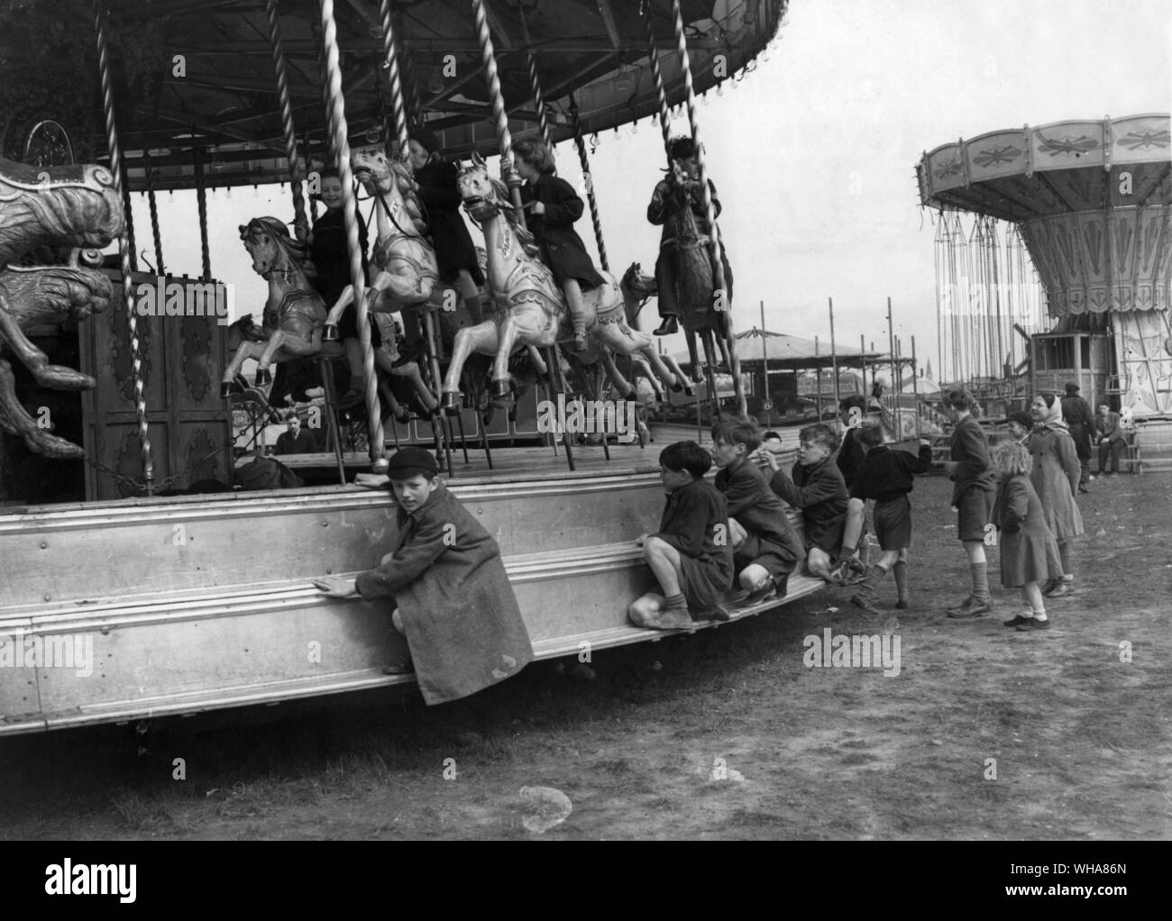 Die Szene in der Blackheath Fair wie Jugendlichen helfen, sich selbst zu einem freie Fahrt im Kreisverkehr. 12. April 1952 Stockfoto