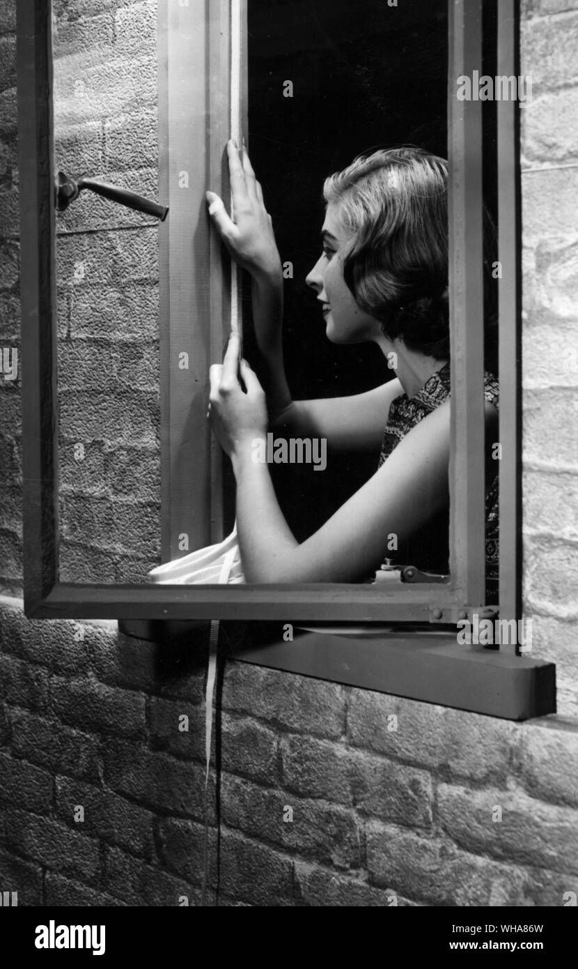 Frau fitting Entwurf der Abstreifdichtung an einen Fensterrahmen Stockfoto