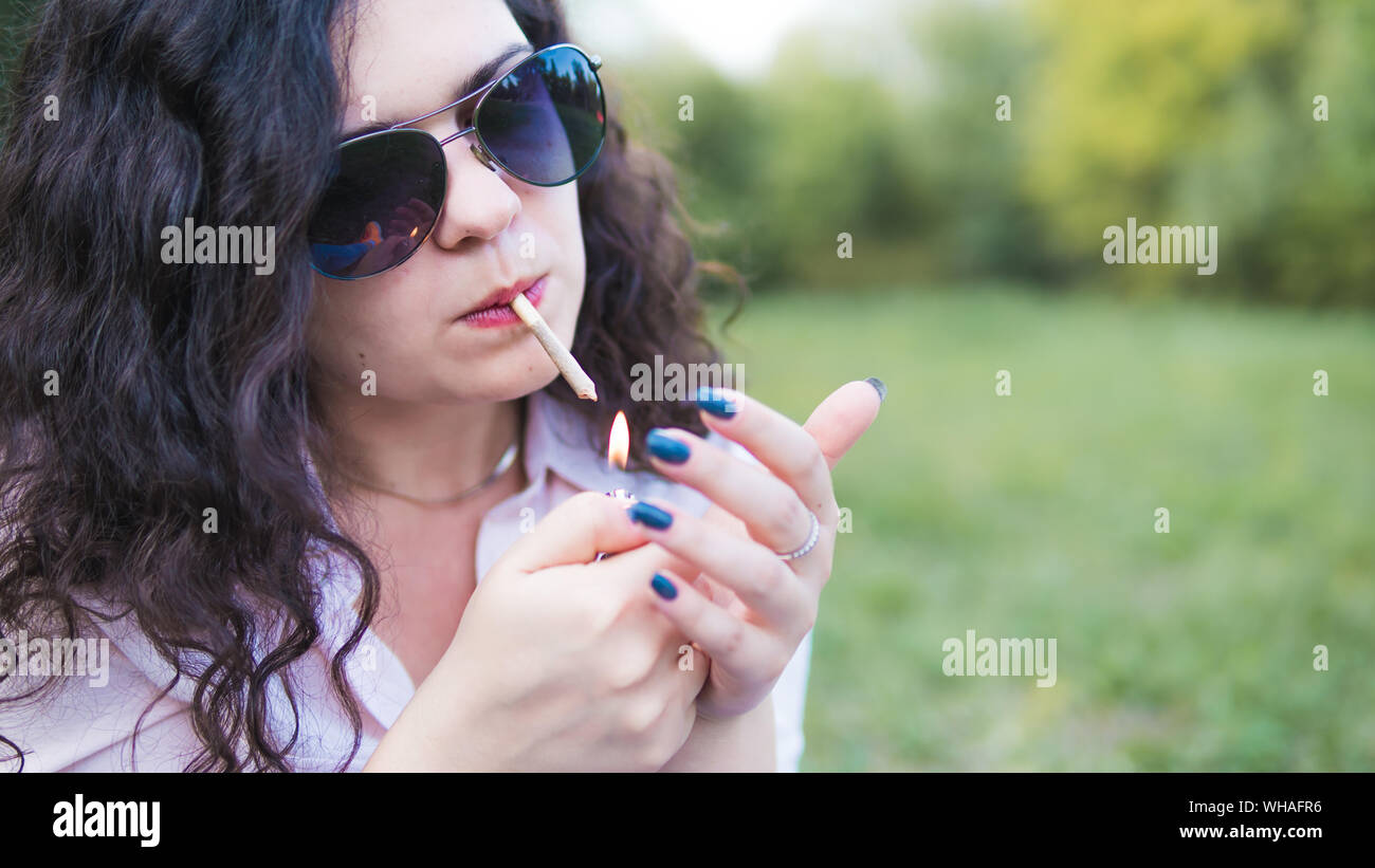 Mädchen rauchen Marihuana gemeinsame im Freien. Die jungen Frauen rauchen Cannabis Blunt, close-up. Cannabis ist ein Konzept der Kräutermedizin. Stockfoto