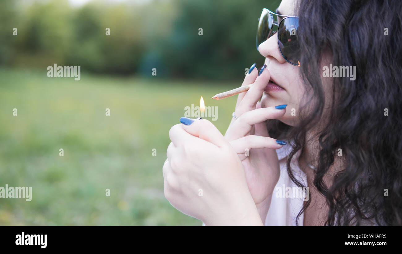 Mädchen rauchen Marihuana gemeinsame im Freien. Die jungen Frauen rauchen Cannabis Blunt, close-up. Cannabis ist ein Konzept der Kräutermedizin. Stockfoto