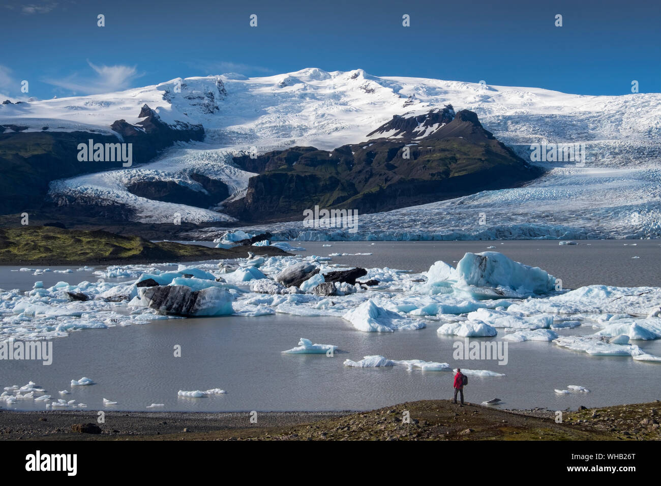 Walker mit Blick auf die Fjallsarlon Lagune, die vom Vatnajokull-Gletscher in der Nähe von Hofn, Südisland, umgeben ist. MODELL FREIGEGEBEN Stockfoto