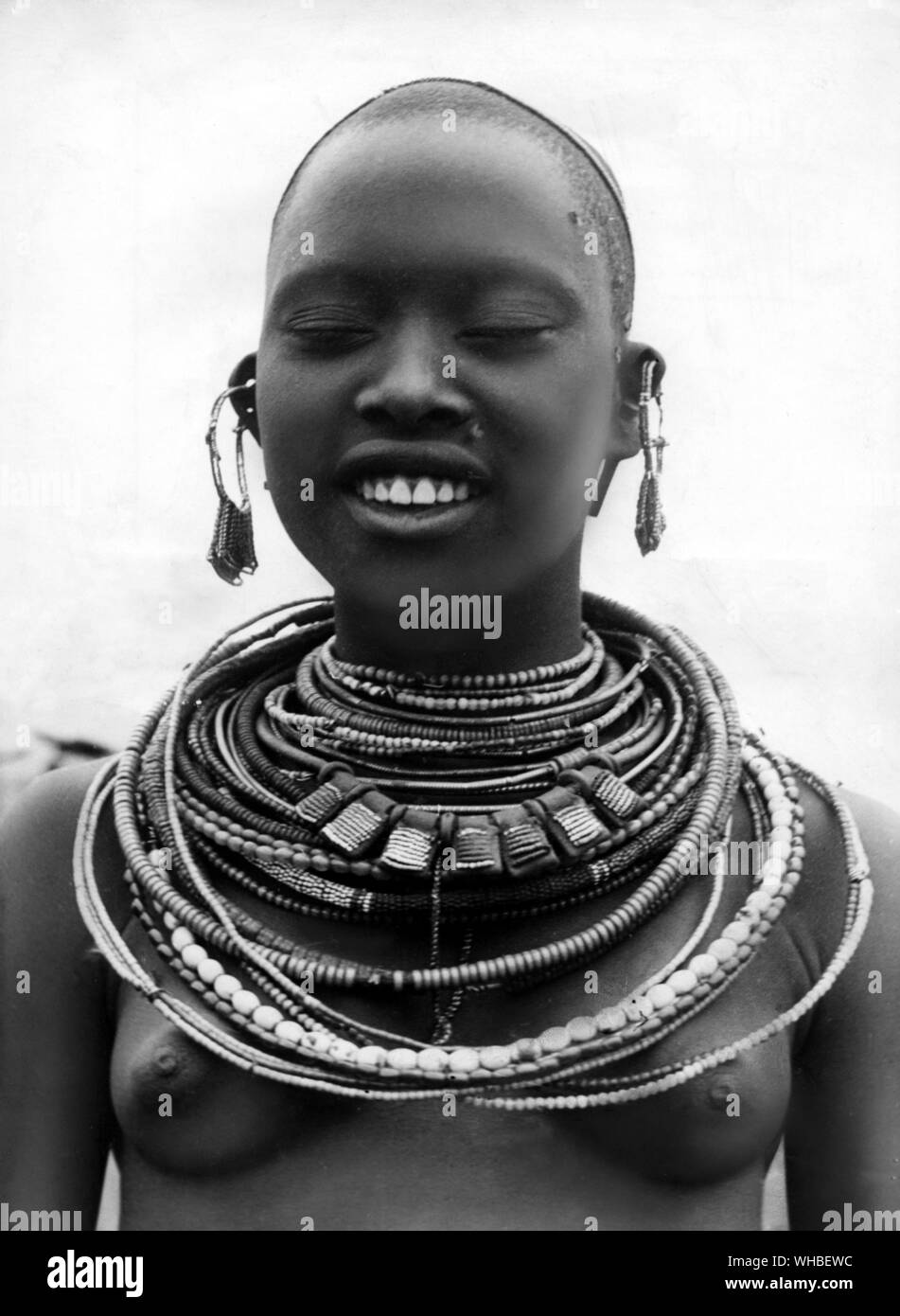 Perlen in jeder Größe und jeder Farbe schmücken den Hals des jungen Massai Mädchen. Stockfoto