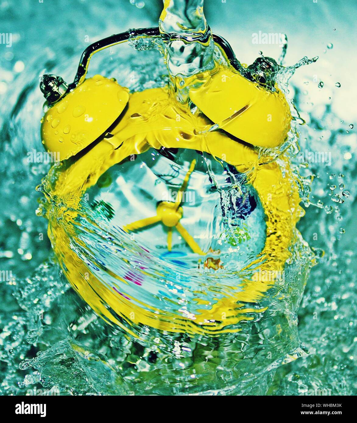 Eine konzeptuelle Fotografie eine kleine gelbe Uhr in Wasser die Zeit zu stoppen. Stockfoto