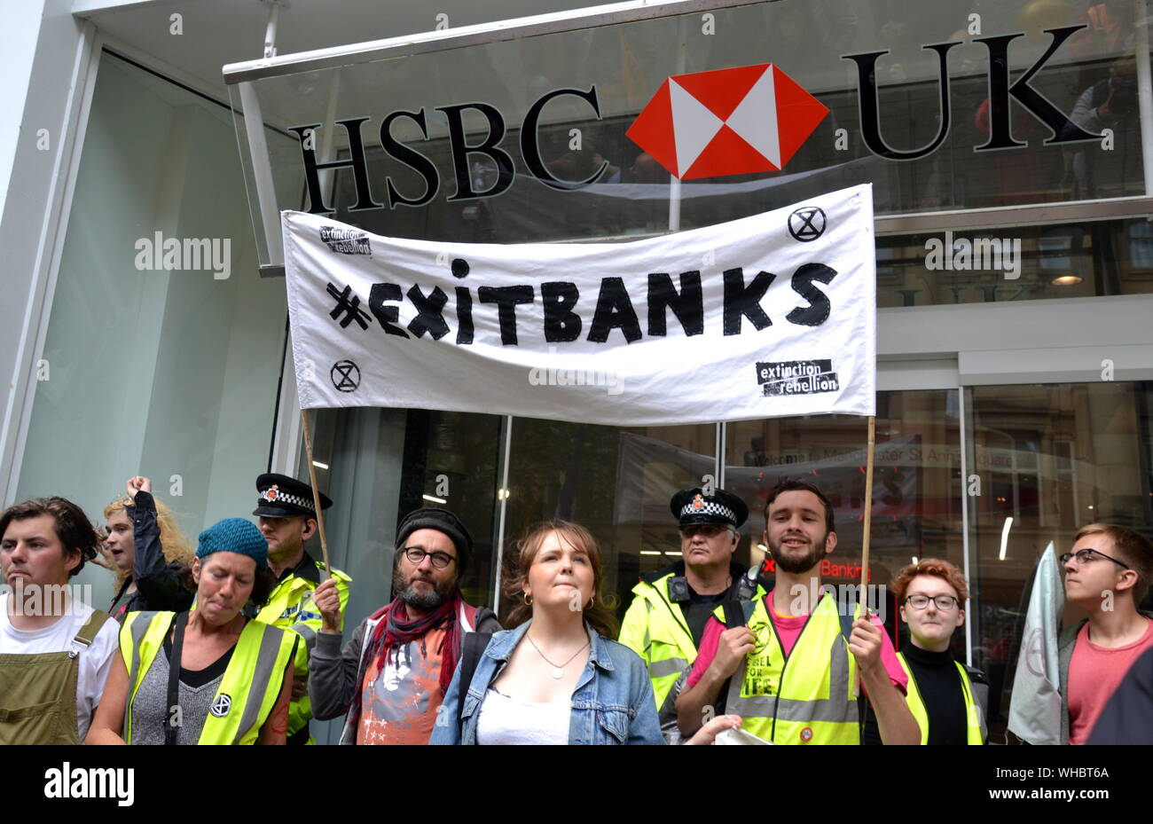 Die Demonstranten der Nordaufstand, die Teil der globalen Bewegung Extinction Rebellion sind, halten vor der HSBC Bank auf dem St. Anne's Square, Manchester, Großbritannien, ein Banner mit den „Exit Banks“. Die Demonstranten marschierten durch Manchester, großbritannien, und hielten am 2. September 2019 eine Reihe von Eindringinnen ab, um Maßnahmen gegen den Klimawandel zu fordern. Zu den Protestseiten gehörten die Barclays Bank, ein Primark-Geschäft und die HSBC Bank. Dies war der vierte Tag eines Protestes, der Deansgate, eine Hauptstraße im Zentrum von Manchester, blockierte. Stockfoto