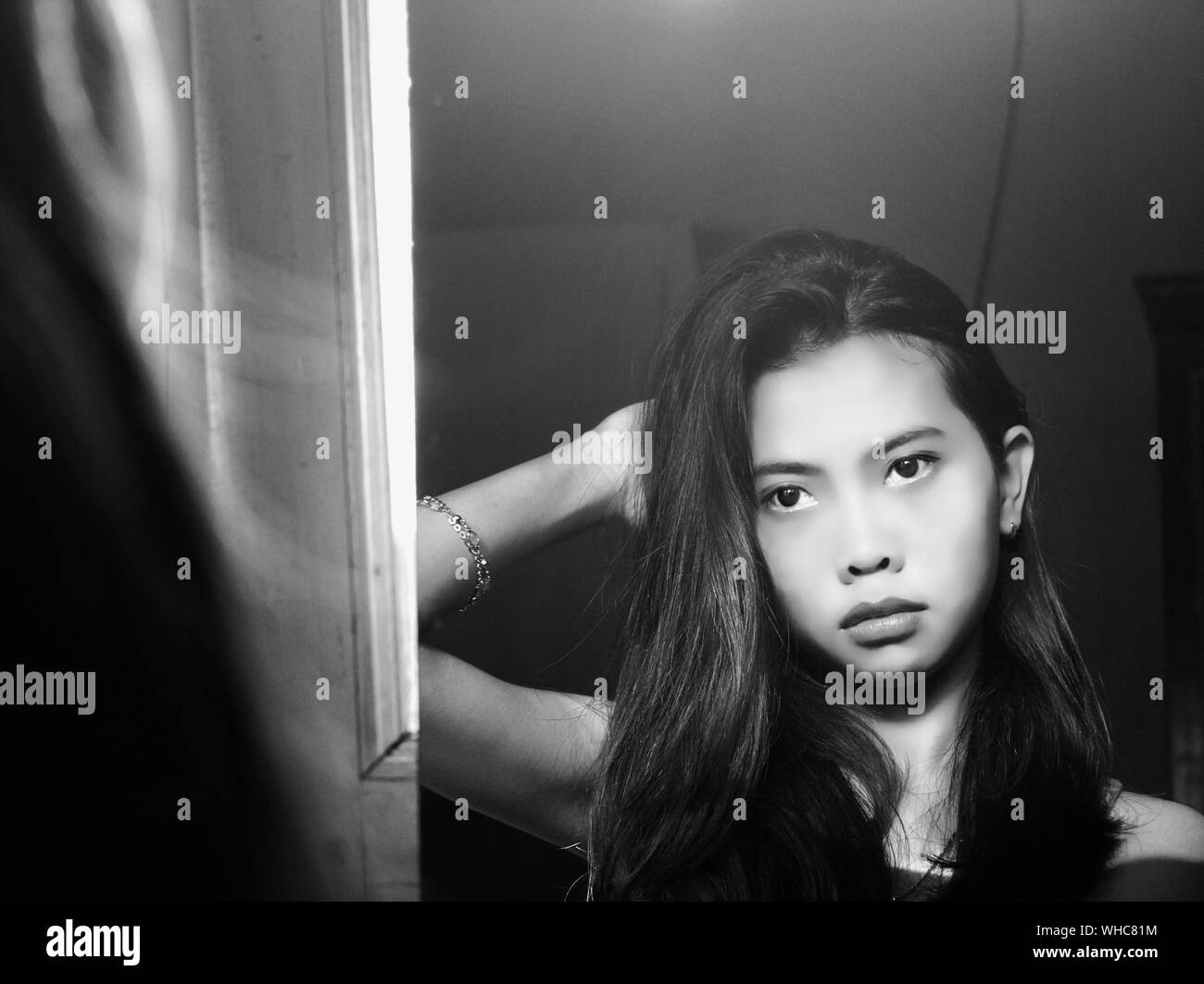 Junge frau, die in der hand spiegel schaut Schwarzweiß-Stockfotos und