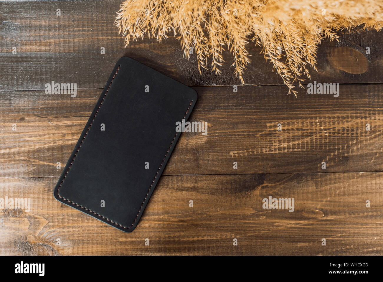 Teuer, schönes Cover von eco-Leder auf einem Hintergrund von Holz und Weizen. Schöne Natur Care Concept. Handgefertigte Phone Case in der Farbe schwarz. Stockfoto