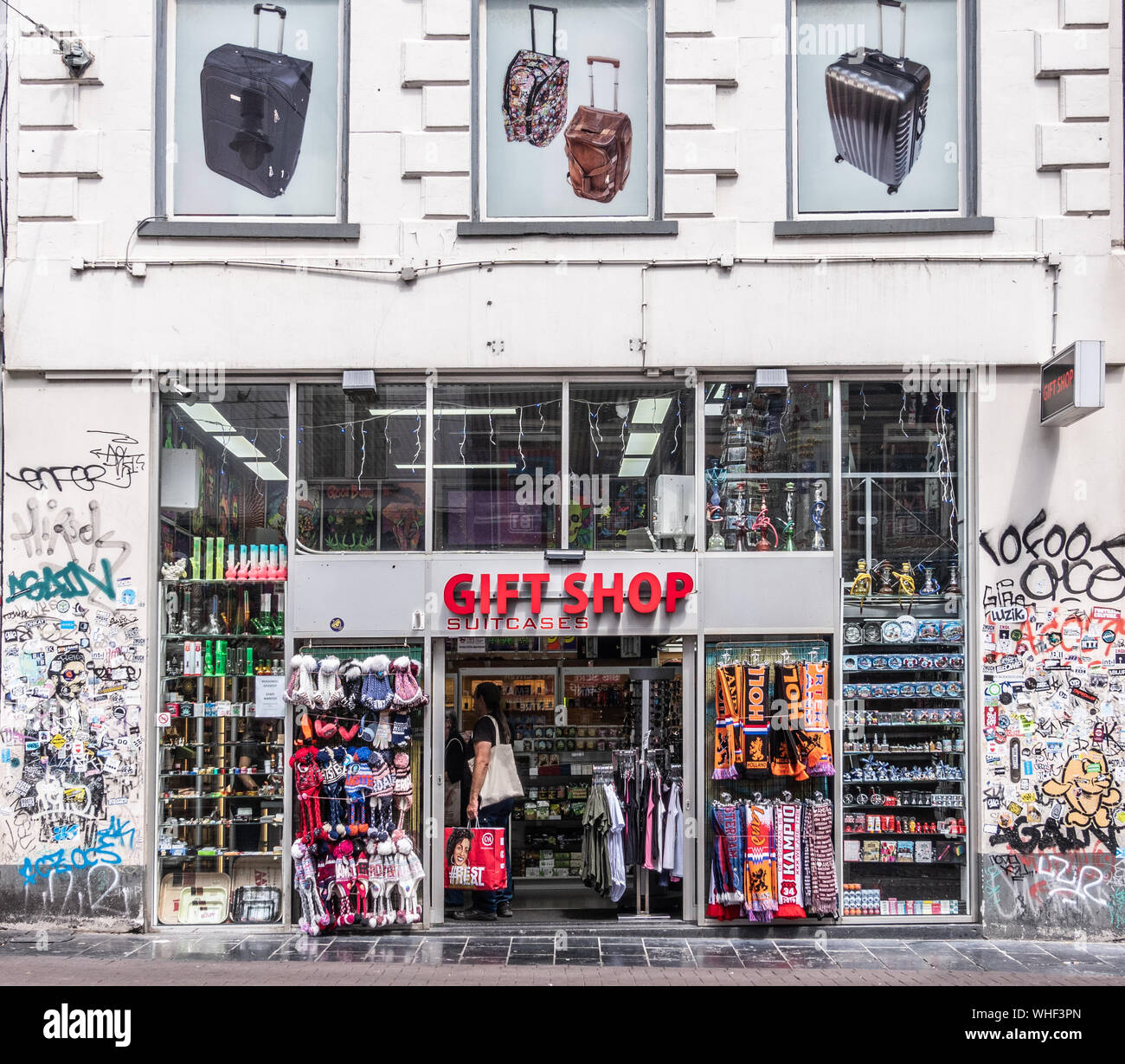 Amsterdam, Niederlande - 1 Juli, 2019: Geschenk Shop Eingang und Fassade mit der Menüpunkte auf der Anzeige in der weissen Mauer in Graffiti und Aufkleber abgedeckt. Stockfoto