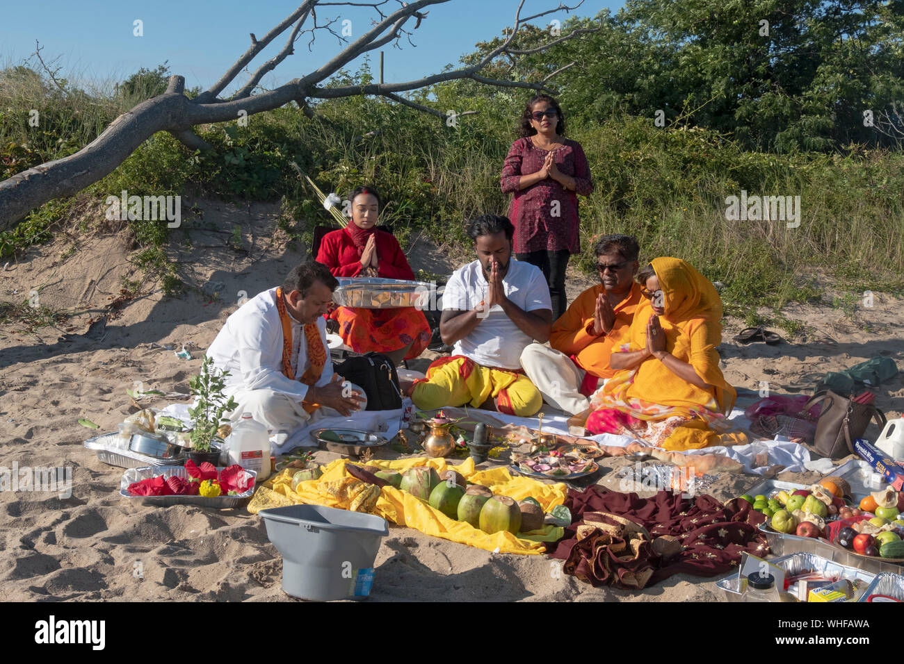 Ein frommer Hindu Familie in einem Gebet Service im Freien an einem Strand an der Jamaica Bay in Queens, New York, teil. Stockfoto