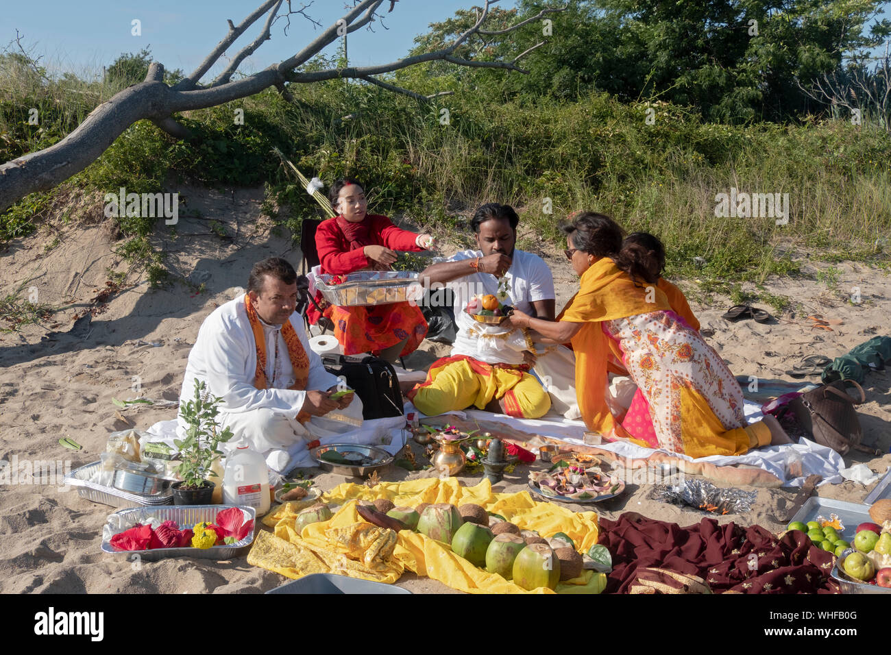 Ein frommer Hindu Familie in einem Gebet Service im Freien an einem Strand an der Jamaica Bay in Queens, New York, teil. Stockfoto