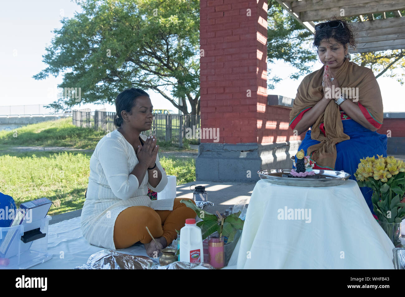 Ein frommer Hindu Frau feiert ihren Geburtstag mit einer Puja Service im Freien auf Jamaica Bay in Queens, New York City. Stockfoto