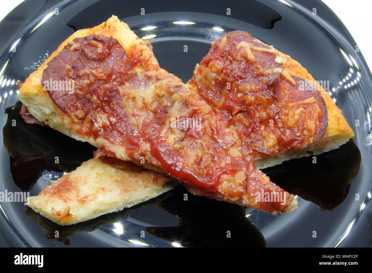 Pizza Schnitten auf einer schwarzen Platte. Pizza auf schwarzem Teller. Stockfoto