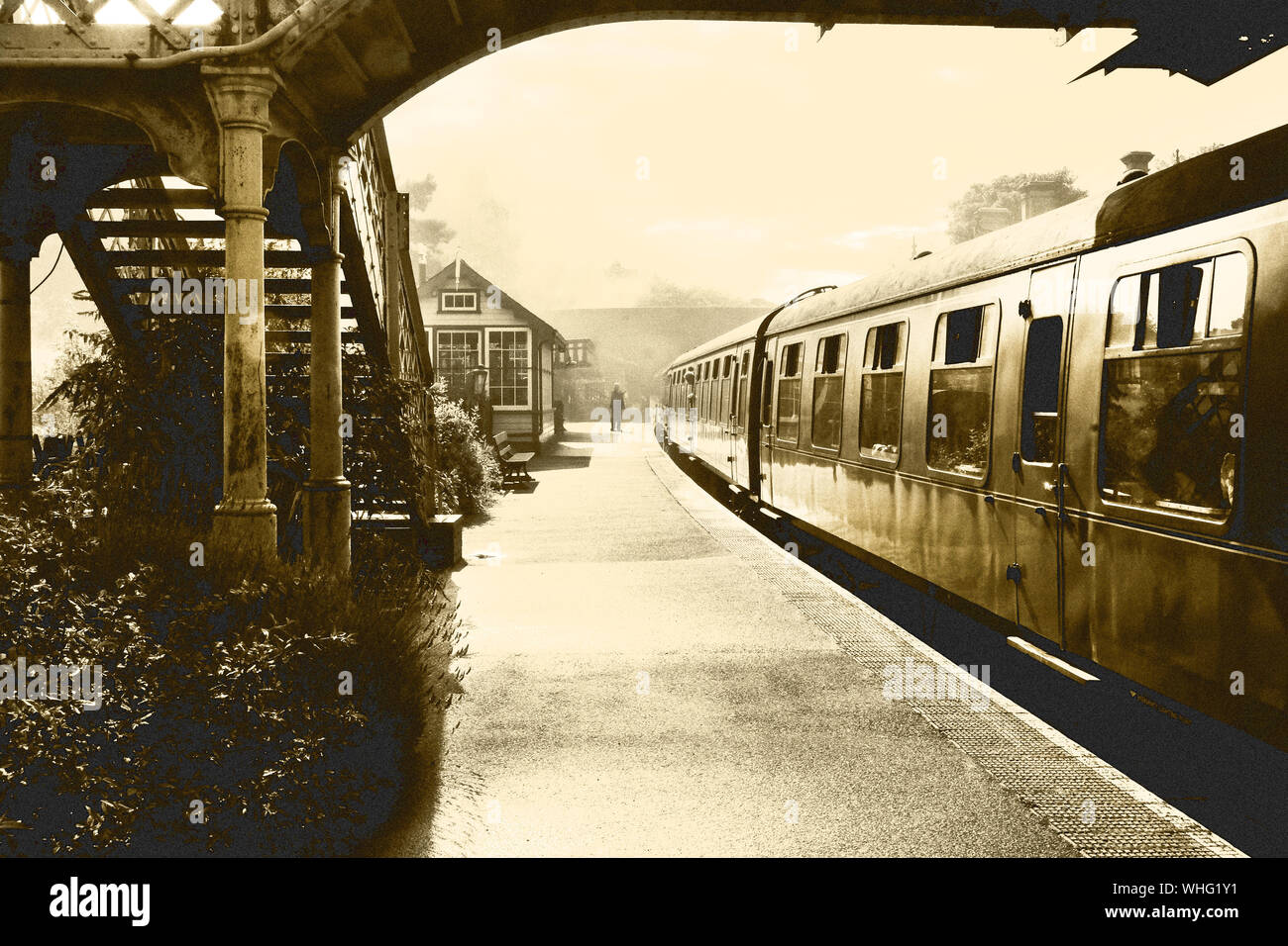 Schwarze und weiße retrospektive Foto einer Dampfeisenbahn und carraiges am Bahnhof Weybourne, Norfolk, England, UK, die Plattform ist neblig und in der d Stockfoto