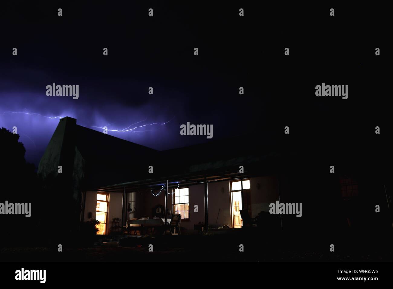 Schöne Aufnahme eines Hauses mit Licht und Blitz In einem dunklen Himmel im Hintergrund Stockfoto