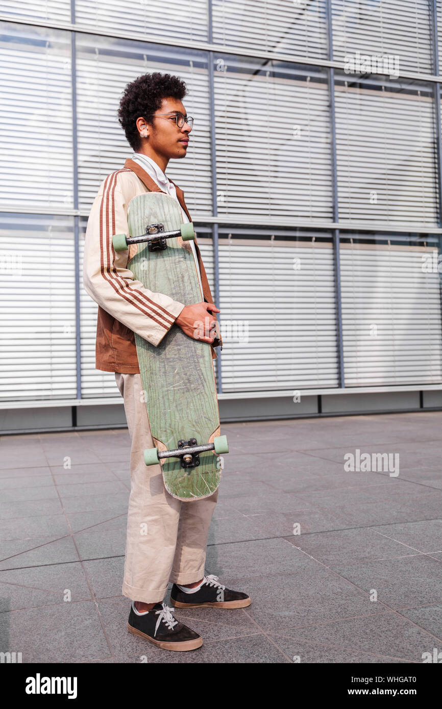 Skateboarder steht mit seinem Skateboard in der Stadt Stockfoto