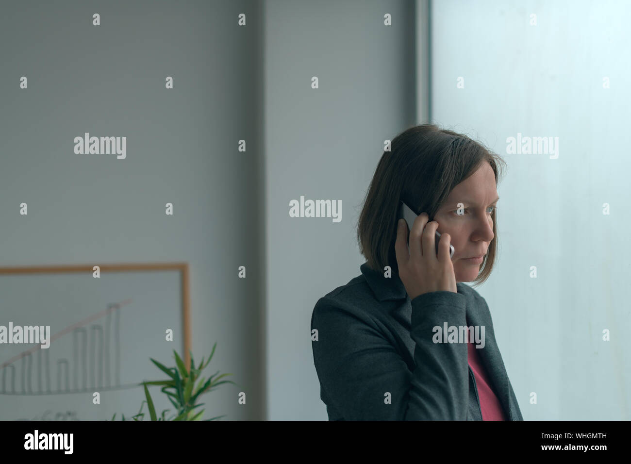 Im Handy Gespräch vom Amt Fenster Geschäftsfrau, erwachsenen weiblichen kaukasischen business Person auf dem Smartphone Stockfoto