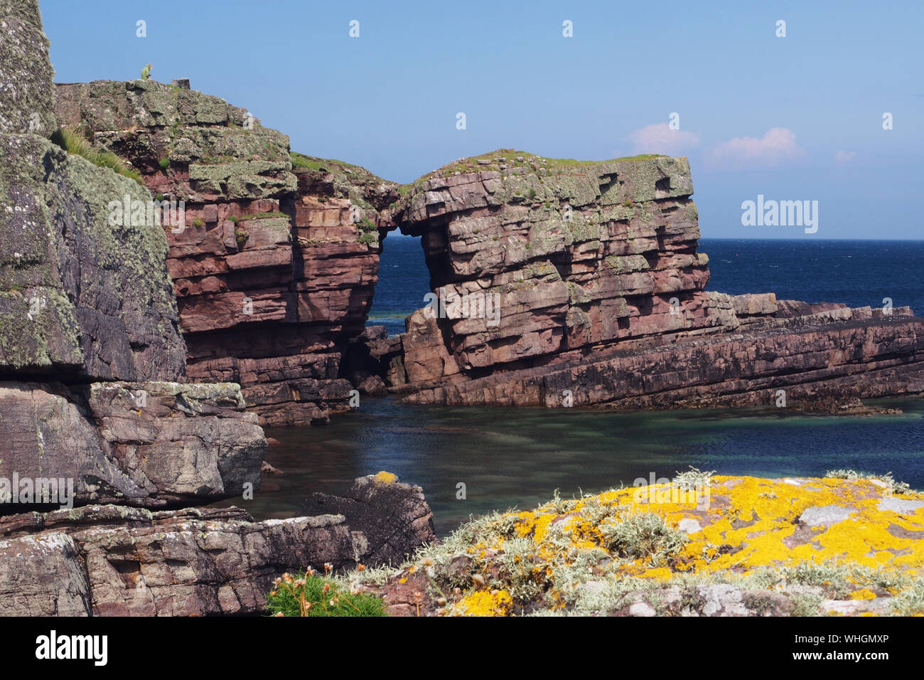 Blick über das Meer zu einem Natural Arch und Felsen in der Nähe von Culkein, Sutherland, Schottland mit vielen natürlichen Farben im Meer und auf die Felsen Stockfoto