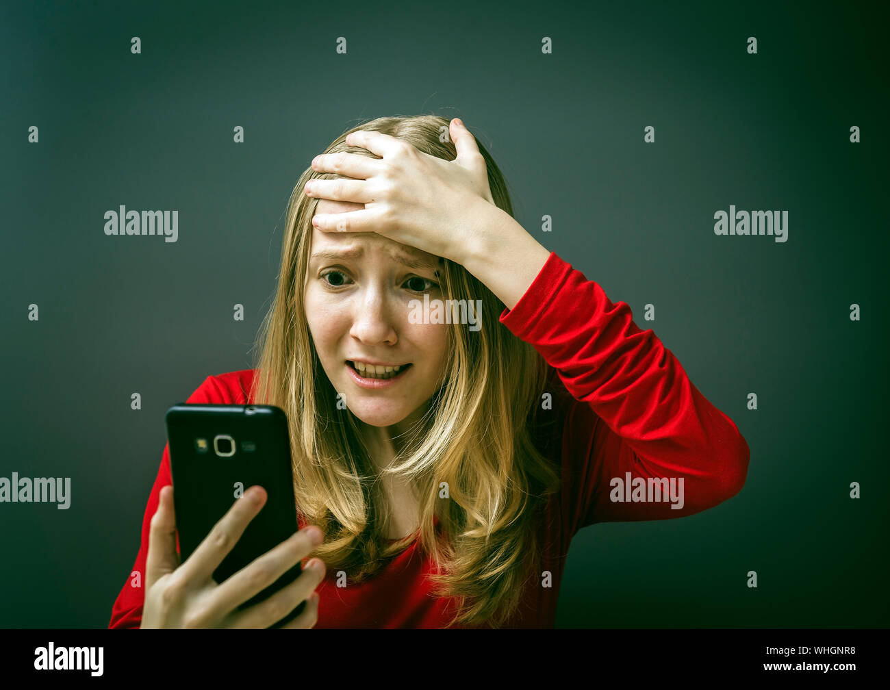 Close-up sorgen junge Frau mit Telefon vor grauem Hintergrund Stockfoto
