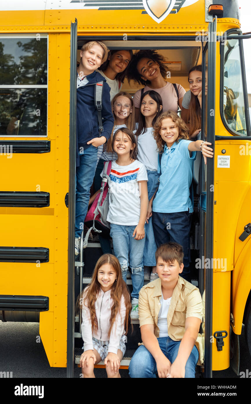 Gruppe von Kindern Mitschüler gehen mit dem Bus sitzen auf der Treppe zur Schule posiert für die Kamera zusammen lächeln fröhlicher Stockfoto