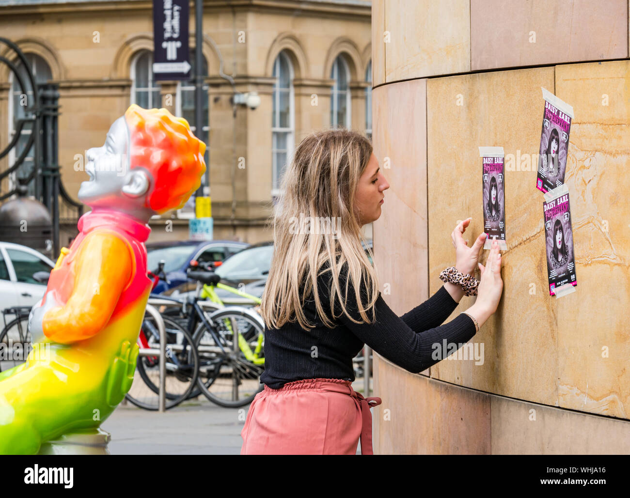 Oor Wulie Zeichentrickfigur schaufel Art Trail & junge Frau buchung Flyer an der Wand des Nationalen Museums während Fringe Festival, Edinburgh, Schottland, Großbritannien Stockfoto