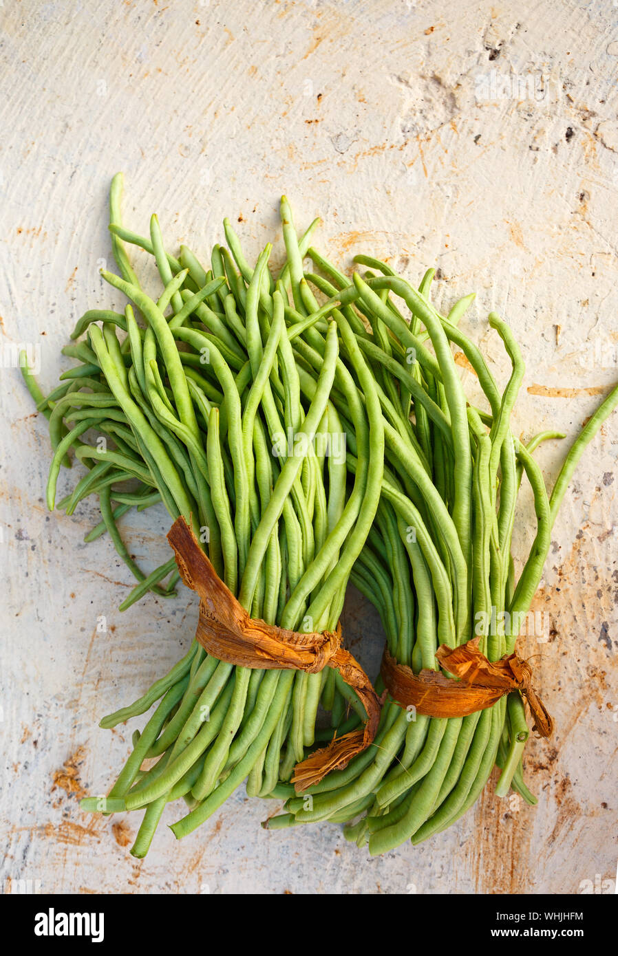 Ansicht von oben von zwei Trauben von kubanischen grüne Bohnen auf einem weißen Betonoberfläche Stockfoto