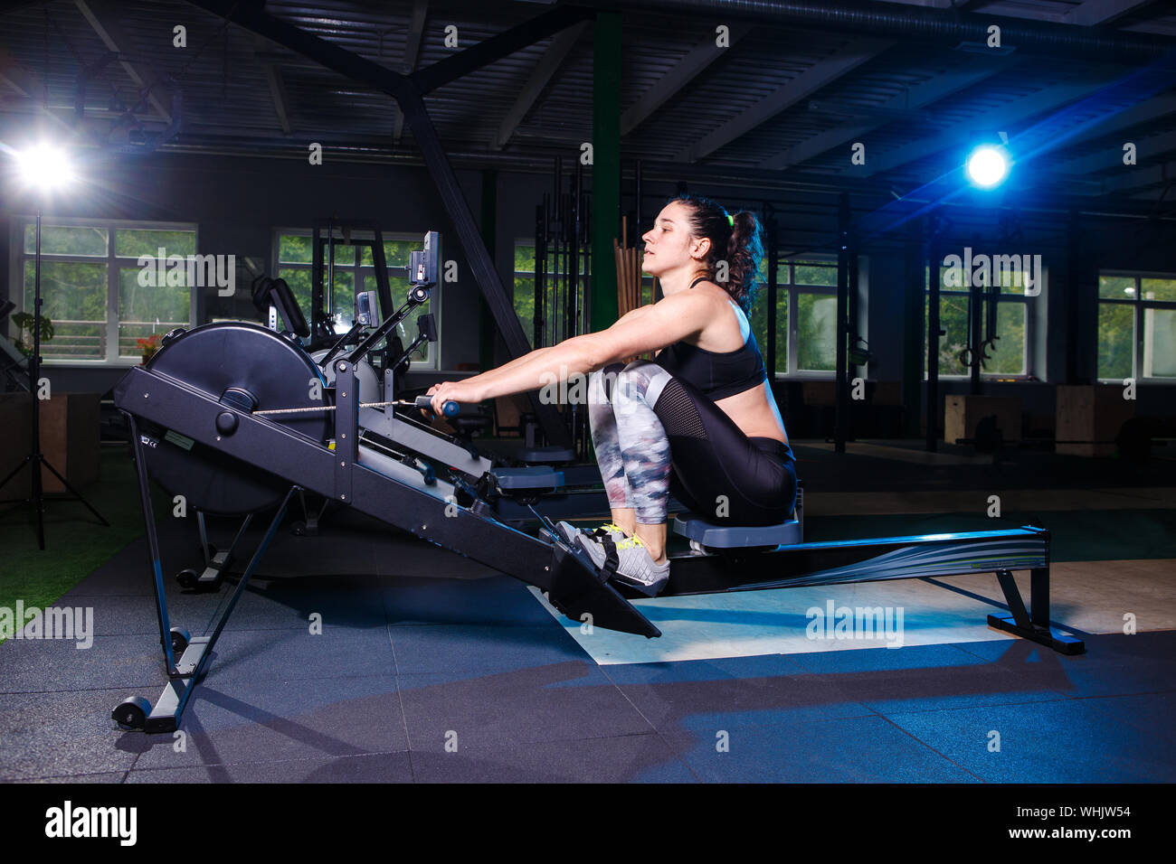 Junge starke Mädchen tun, eine Übung auf einem Rudergerät. Für Training cardio Arme, Rücken. Sportliche Konzepte Stockfoto