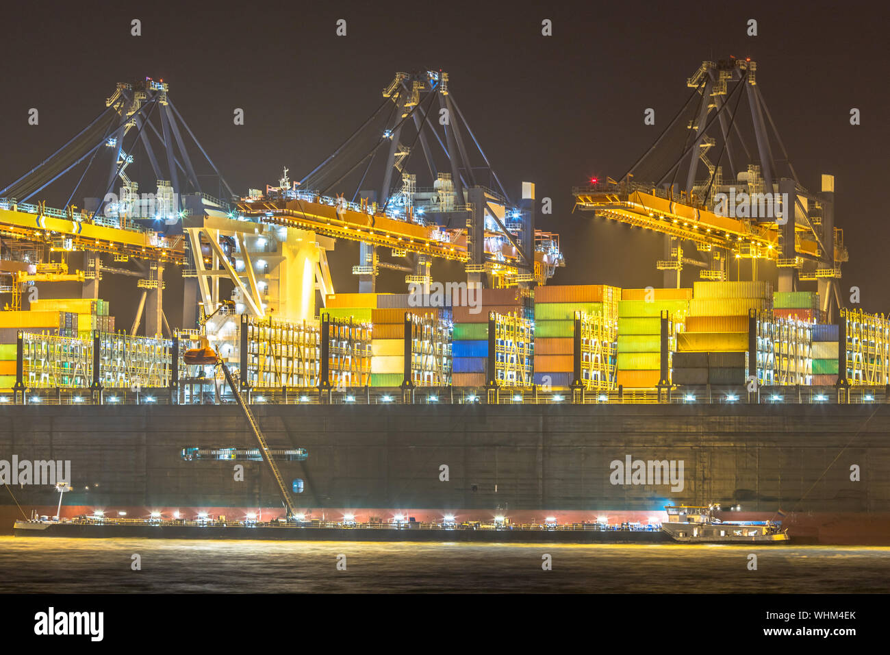 Beleuchtete Cargo Carrier Schiff verladen und in der Nacht in Rotterdam Maasvlakte Container Terminal in der Dunkelheit betankt. Die Niederlande Stockfoto