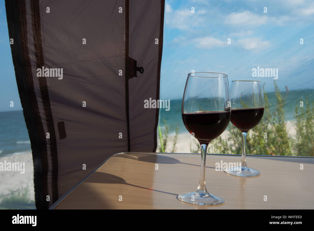 Luxus camping, eine Ansicht aus einem Camp Zelt auf einem Meer und zwei Gläser Rotwein Stockfoto