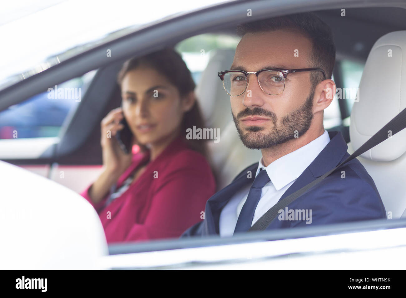 Der bärtige Mann fahren Auto, während Frau sprechen über das Telefon Stockfoto