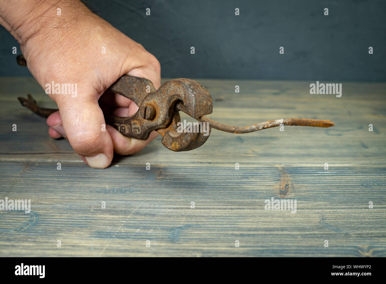 Männliche Hand, die alten rostigen Griffe und lange gebogene korrodierte Nagel über einen rustikalen Holztisch in der Nähe zu sehen. Stockfoto