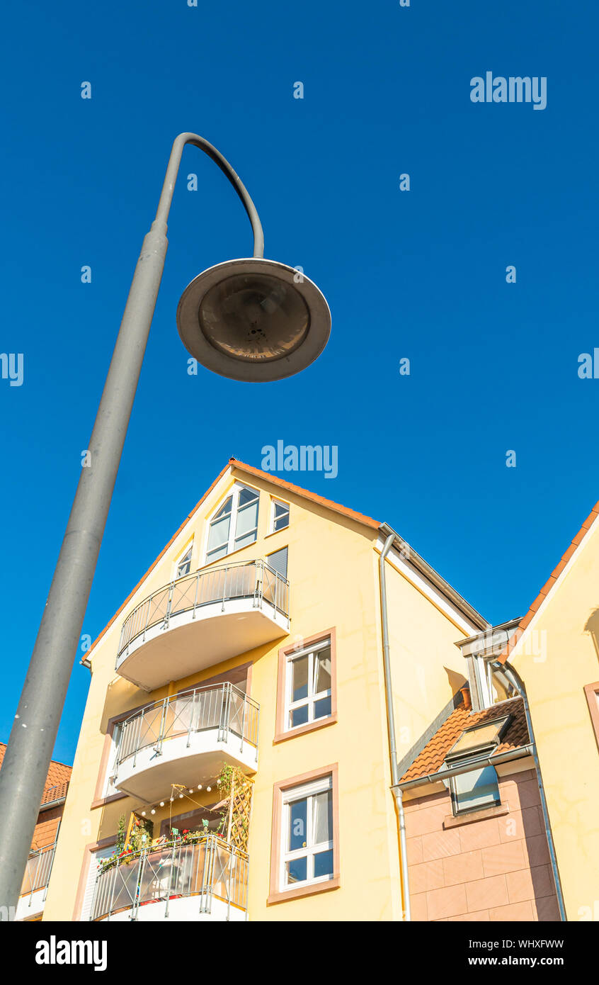Straßenlaterne unter einem Wohnhaus. Gelbe Gebäudefassade. Große Fenster in der Wohnung. Unter einem blauen Himmel. Stockfoto