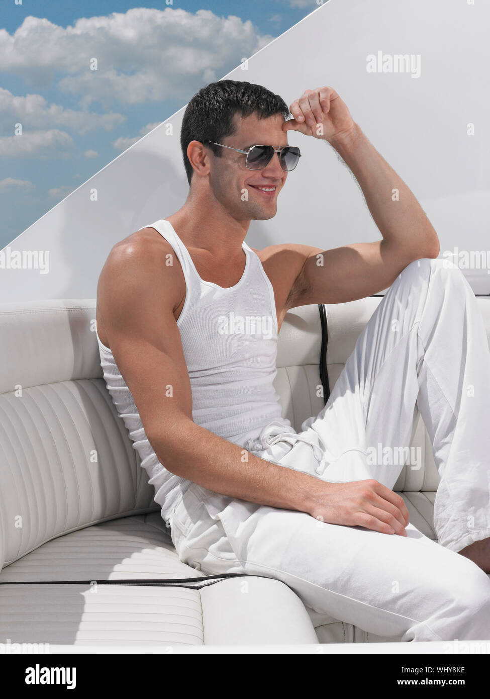 Lächelnden jungen Mann mit Sonnenbrille beim Sitzen auf einem Sofa in Yacht Stockfoto